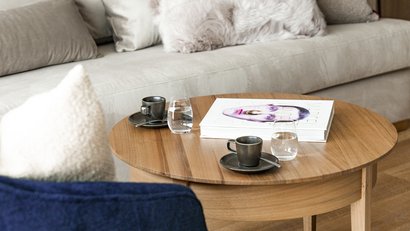 Holztisch mit zwei Kaffeetassen, Wassergläsern und einem Kunstbuch im Wohnzimmer