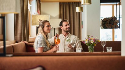 Paar sitzt in gemütlicher Bar und hält Drinks in der Hand