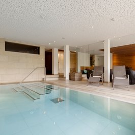 Moderner Innenpool mit Liegestühlen und Holzverkleidung