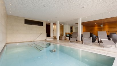 Moderner Innenpool mit Liegestühlen und Holzverkleidung