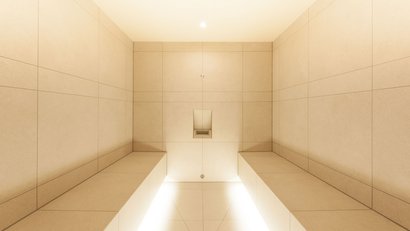 Minimalistischer Duschraum mit beige Fliesen und Sitzbänken