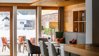 Gemütlicher Essbereich mit Sitzplätzen innen und außen im verschneiten Bergort