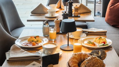 Gemütlich gedeckter Frühstückstisch mit Kaffee, Orangensaft und Brötchen
