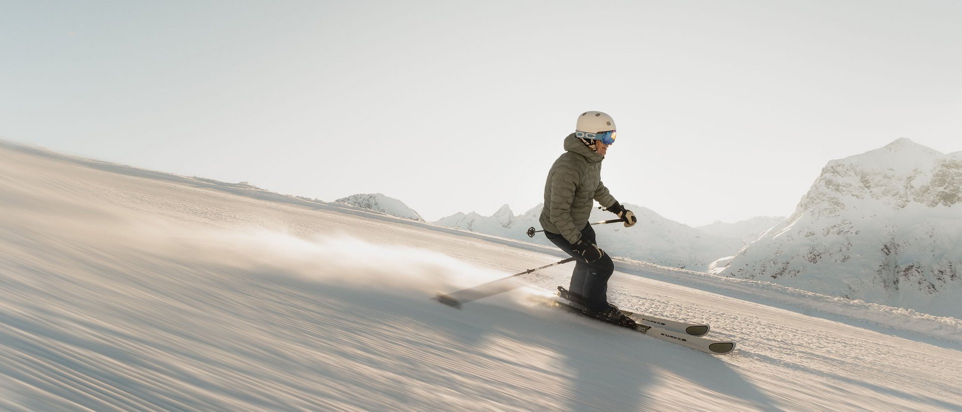 Skier descending snowy slope in mountains during sunlight