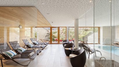 Moderner Ruheraum mit Liegestühlen und Sitzbereich neben einem Innenpool