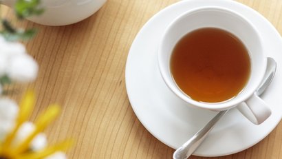 Tasse Tee mit Teekanne und Schale getrockneter Apfelscheiben auf Holztisch