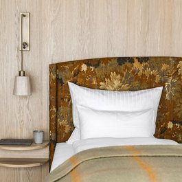 Gemütliches Bett mit gemusterter Kopfstütze, weißen Kissen und Nachttisch