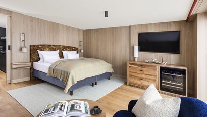 Gemütliches Schlafzimmer mit Holzverkleidung, Doppelbett und TV