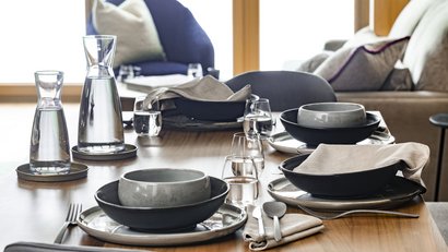 Eleganter gedeckter Esstisch mit Wasserflaschen und modernen Geschirrsets