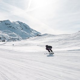 Skifahrer fährt auf einer verschneiten Piste in den Bergen bei sonnigem Wetter