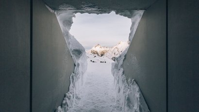 Blick durch enge Tür mit Schnee zu verschneiten Bergen bei Tageslicht